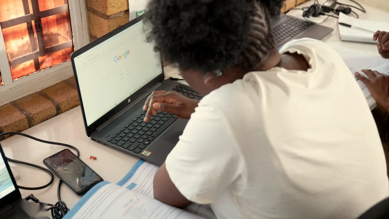 A learner using a keyboard with a Google search on the laptop screen