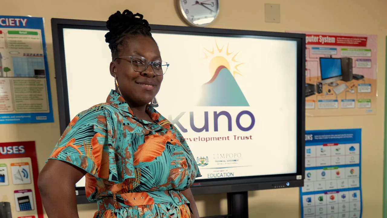 A woman smiling in front of the Dikuno logo on the interactive screen