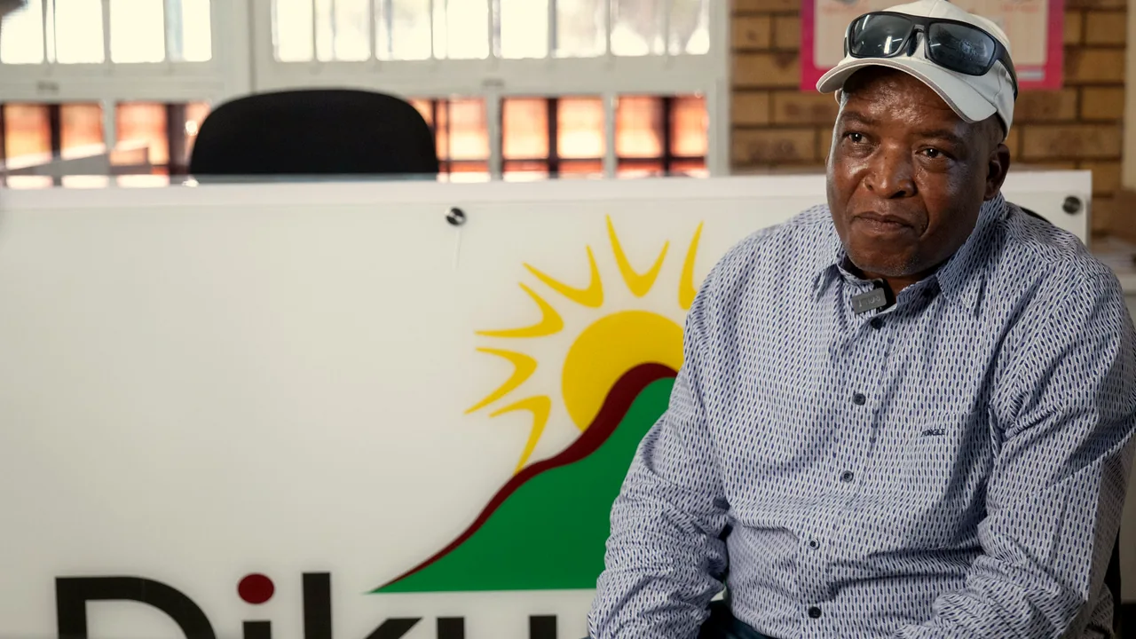 A man seated in front of the Dikuno sign at the centre