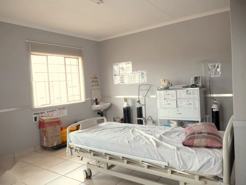 A clinic ward with a bed, oxygen cylinders and a medicine cabinet