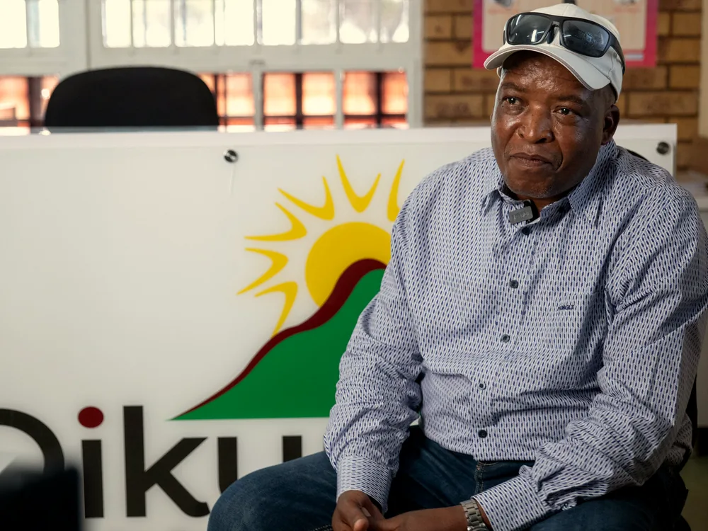 A community member seated in front of the Dikuno sign